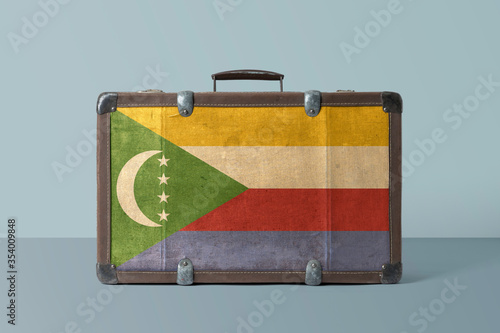 Comoros flag on old vintage leather suitcase with national concept. Retro brown luggage with copy space text.