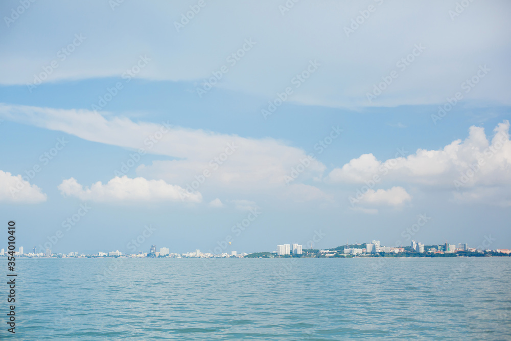 A city far away on the horizon. Sea or ocean shore, buildings and houses, and blue sky with clouds