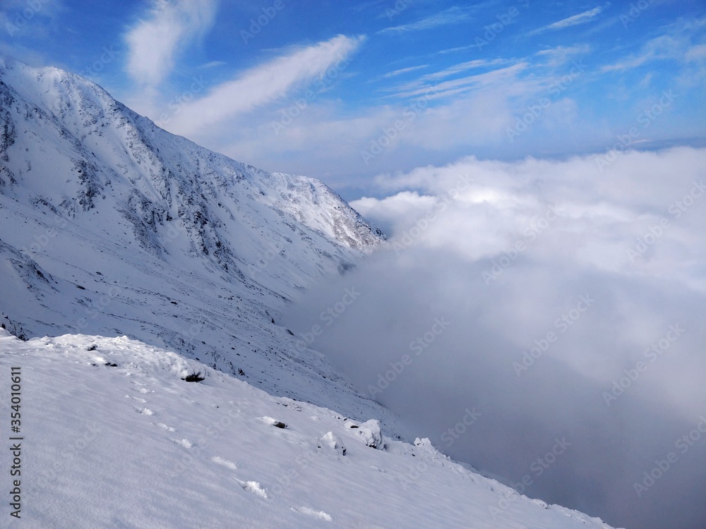 Obraz premium Beautiful view from Himalayan mountain peak with blue sky, white snow and clouds below