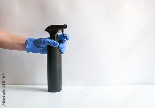 А woman in a glove holds a bottle with a disinfectant. on a white background. Prevention concept. Disinfection and cleaning. Neon colors. Stop Covid-19. copy space, space for text.