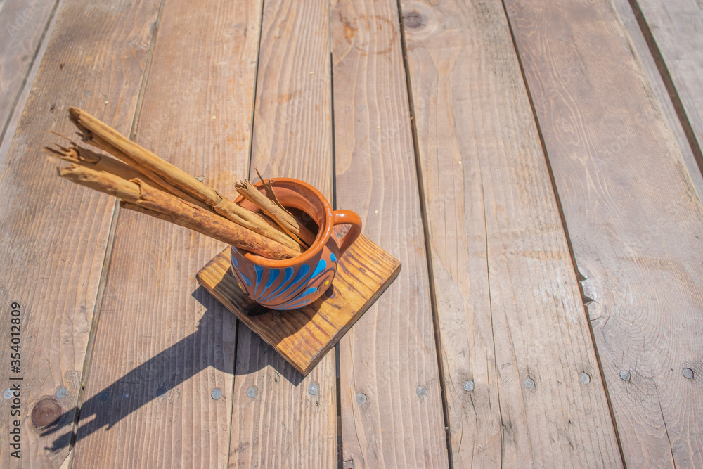 cinnamon in Mexican clay cup, on wooden table cinnamon in Mexican clay cup, on wooden table