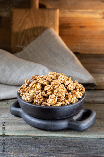 Walnuts in round bowl on wooden rustic background 