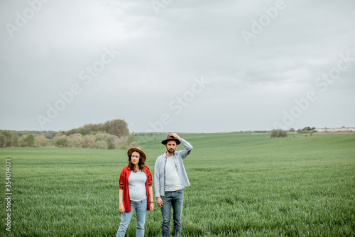 Portrait of a lovely couple standing together on the greenfield. Happy couple expecting a baby  young family concept