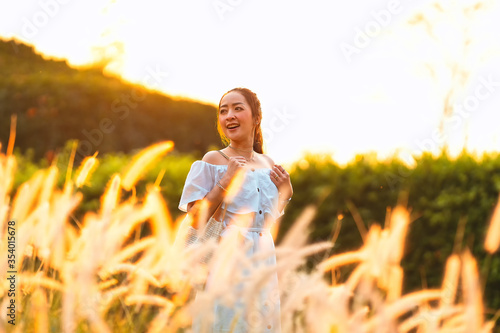 beautiful asian girl in white dress and a hold bag with posing relax in holiday in meadow in sunset light shine