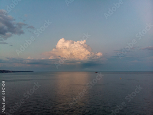 Single cloud ofer the sea and a boat at sunset time © imagestock
