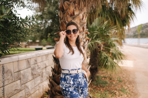 Young woman in blue shorts walking outdoors alone alond the street. Tropical photo