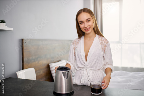 portrait of beautiful young woman going to drink coffee in the morning, attractive lady spend morning in modern kitchen