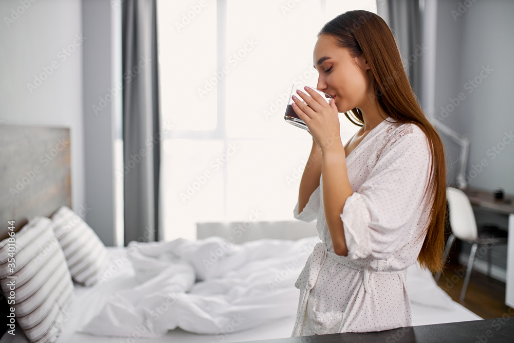 pretty caucasian woman enjoy drinking coffee at home, wearing pajamas. gorgeous lady made a cup of hot coffee for herself pretty caucasian woman enjoy drinking coffee at home, wearing pajamas. gorgeous lady made a cup of hot coffee for herself