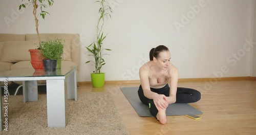 Concentrated woman doing stretching morningn workout exercise on mat at home. photo