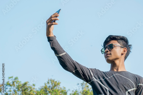 Photography teenager boy wearing sunglasses taking selfie on a mobile outdoor