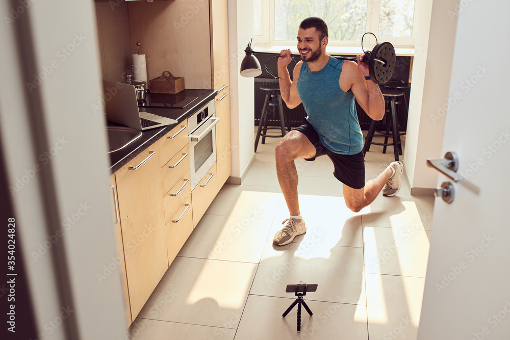Cheerful young man doing exercise with floor lamp