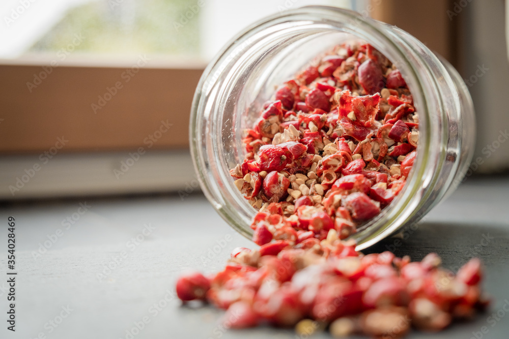 Wild rose hip dry fruit spilled on the black rock surface from glass jar Wild rose hip dry fruit spilled on the black rock surface from glass jar
