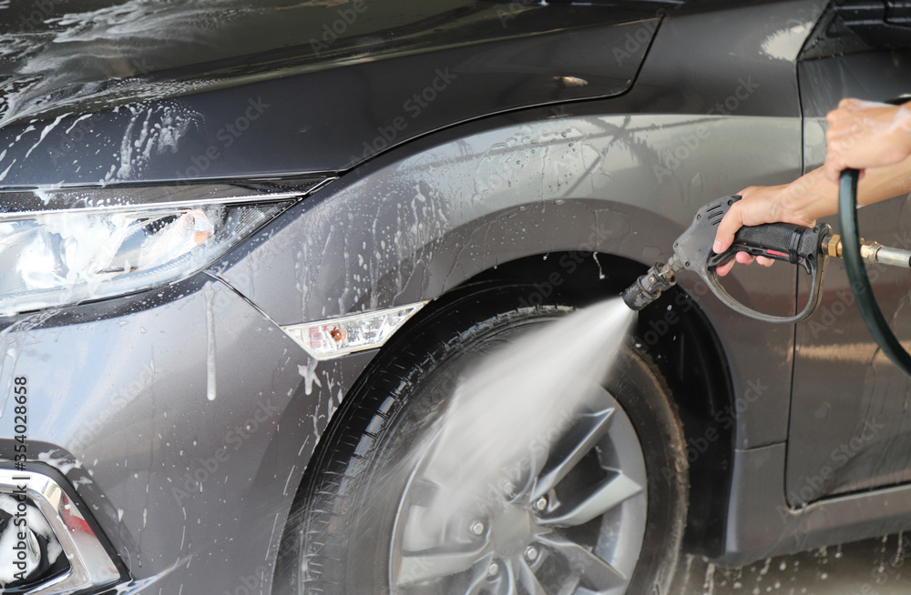 Closeup of grey car cleaning, washing with high pressure water spraying by male worker's hand. Closeup of grey car cleaning, washing with high pressure water spraying by male worker's hand.