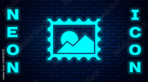 Glowing neon Postal stamp icon isolated on brick wall background. Vector Illustration.