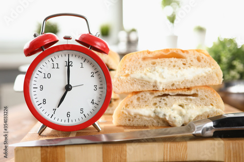 Table an alarm clock and breakfast bread and sauce