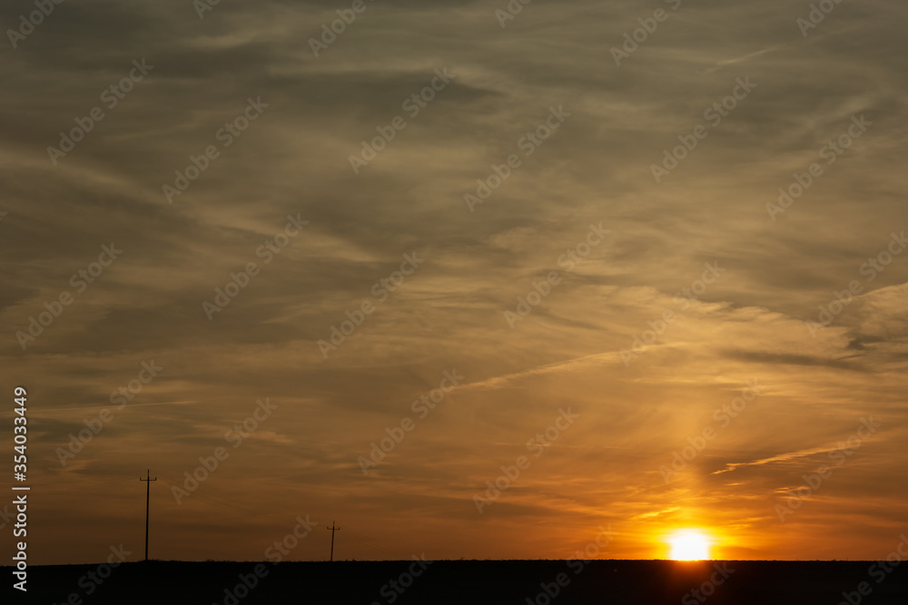 Sunset over the horizon, clouds and electric poles