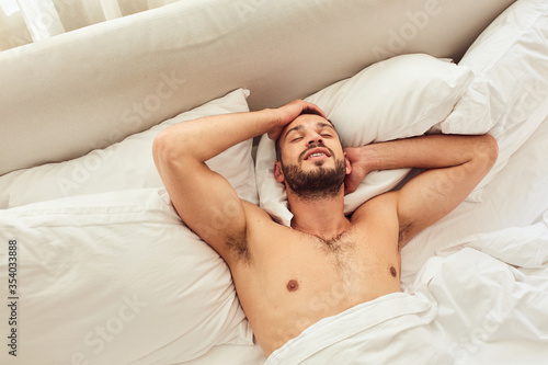 Attractive young man lying in bed at home
