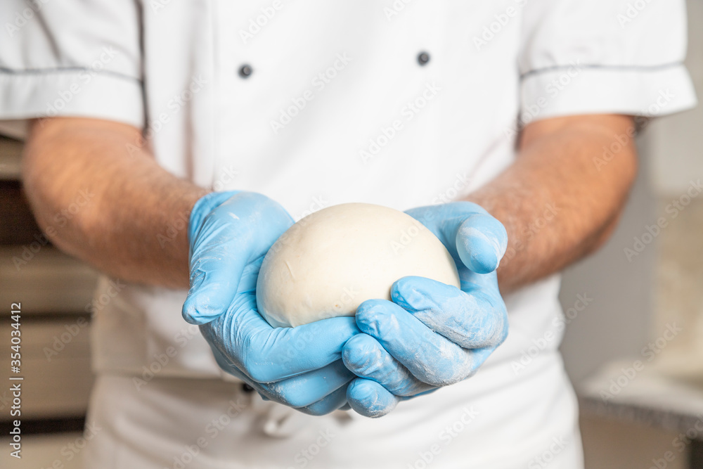 Pizzaiolo baker showing fresh raw dough for pizza or bread baking during covid 19 times- working pizza chef. Pizzaiolo baker showing fresh raw dough for pizza or bread baking during covid 19 times- working pizza chef.
