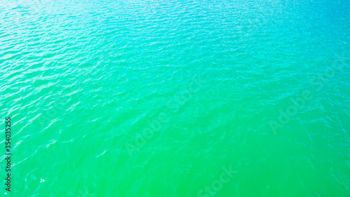 Summer background - turquoise water surface with small waves in the sun light