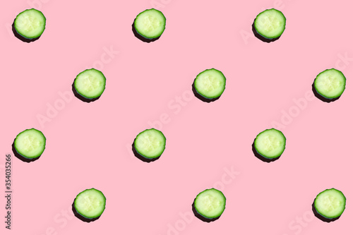 Regular seamless creative pattern of cucumber slices on a pink background.Photo collage,hard lightshadow,pop art design. Food blog, vegetable background. Printing on fabric, wrapping paper.Top view. photo