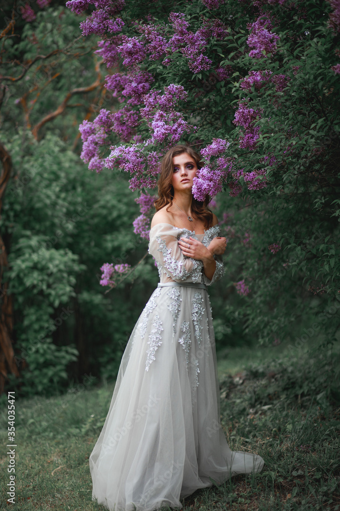 portrait of a girl in a white evening dress next to a lilac Bush portrait of a girl in a white evening dress next to a lilac Bush