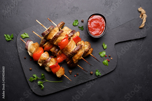 Chicken kebab on skewers with eggplant and red bell pepper on black background. Eggplant and red bell pepper. Food for picnic