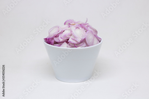 Sliced ​​onions in a white cup on a white background