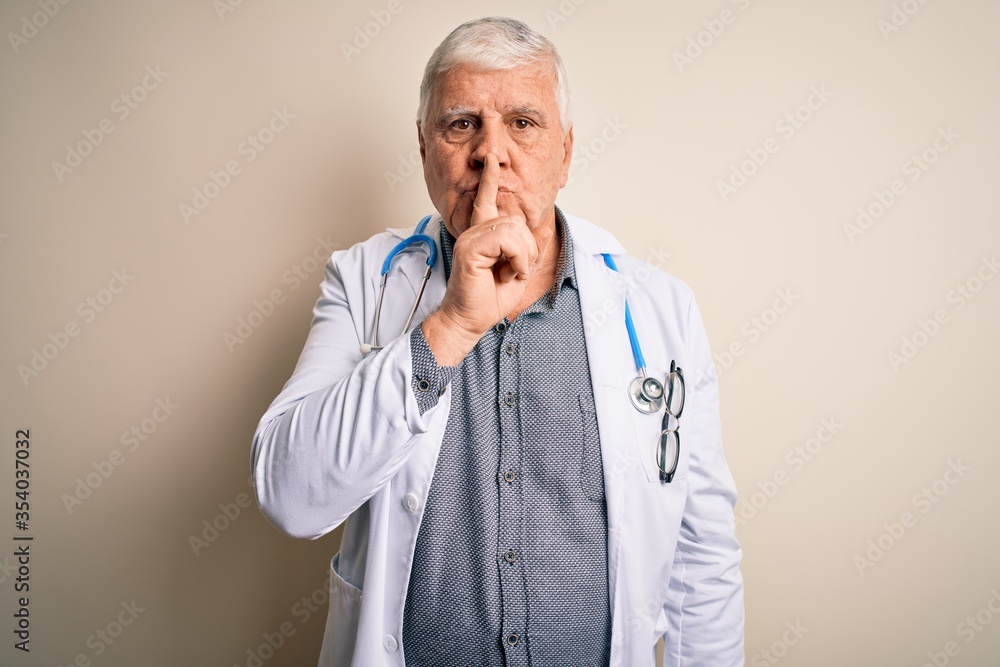 Senior handsome hoary doctor man wearing coat and stethoscope over white background asking to be quiet with finger on lips. Silence and secret concept. Senior handsome hoary doctor man wearing coat and stethoscope over white background asking to be quiet with finger on lips. Silence and secret concept.