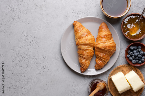 Continental breakfast background. Top view of gray table, croissants, orange juice, coffee, jam and butter