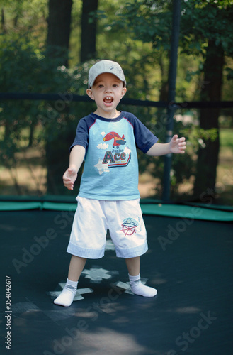 Happy child played in the park with toys. Jump on big batut photo