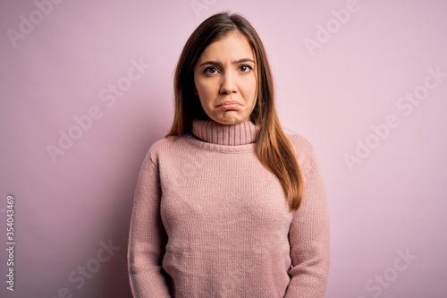 Beautiful young woman wearing turtleneck sweater over pink isolated background depressed and worry for distress, crying angry and afraid. Sad expression. © Krakenimages.com