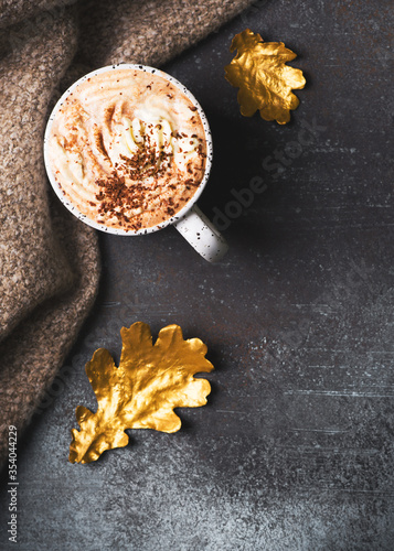Hot chocolate or cup of coffe with foam and with golden leaf on dark background