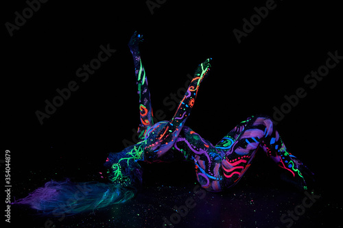 Foto Art woman body art on the body dancing in ultraviolet light