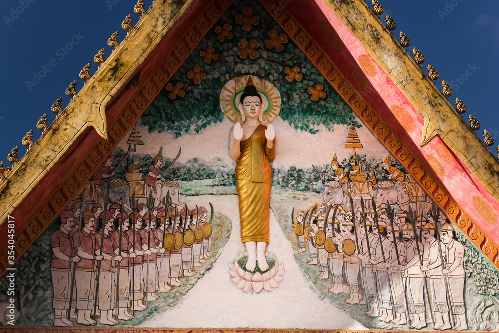 Buddhist painting on the pediment side of the main hall of a wat showing a religious scene in Siamese Lao PDR, Southeast Asia