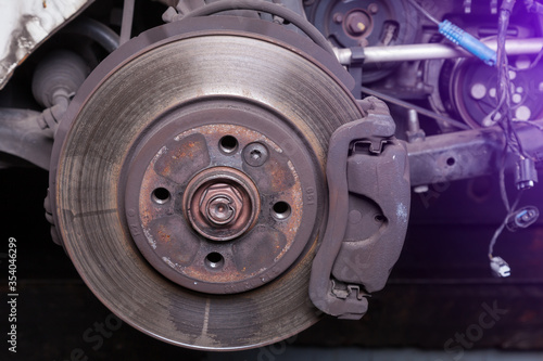 Close-up metal disk in blue backlight - main element of brake system. Friction surface for brake pads. When braking, the pads are pressed against the disk and, due to the friction force, stop rotation