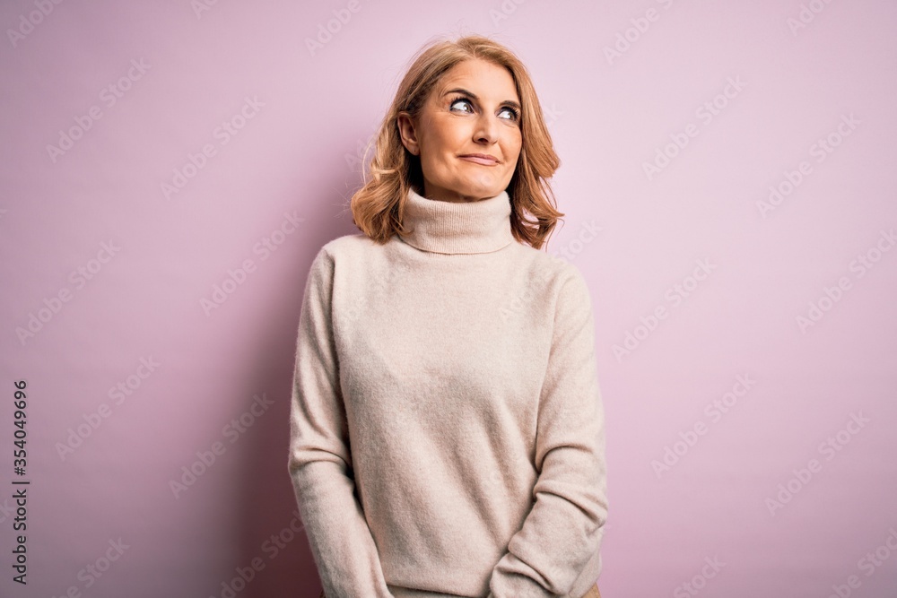 Obraz premium Middle age beautiful blonde woman wearing casual turtleneck sweater over pink background smiling looking to the side and staring away thinking.