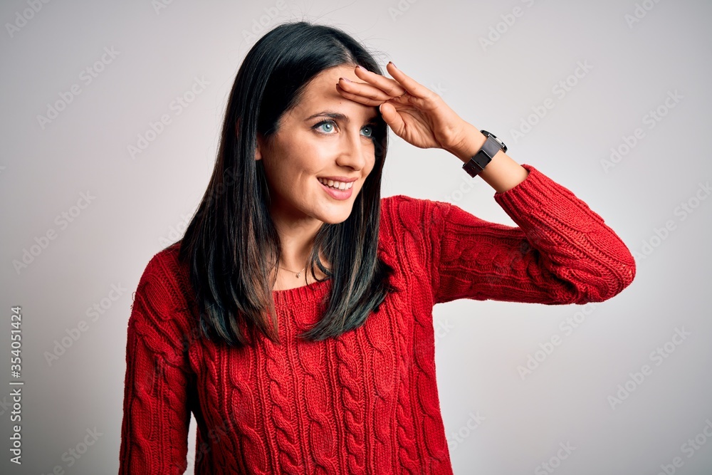 Young brunette woman with blue eyes wearing casual sweater over isolated white background very happy and smiling looking far away with hand over head. Searching concept. Young brunette woman with blue eyes wearing casual sweater over isolated white background very happy and smiling looking far away with hand over head. Searching concept.