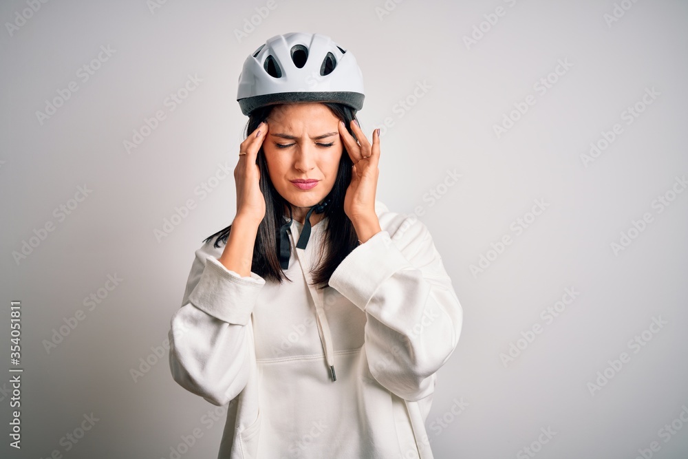 Young cyclist woman with blue eyes wearing bike helmet over isolated white background suffering from headache desperate and stressed because pain and migraine. Hands on head. Young cyclist woman with blue eyes wearing bike helmet over isolated white background suffering from headache desperate and stressed because pain and migraine. Hands on head.