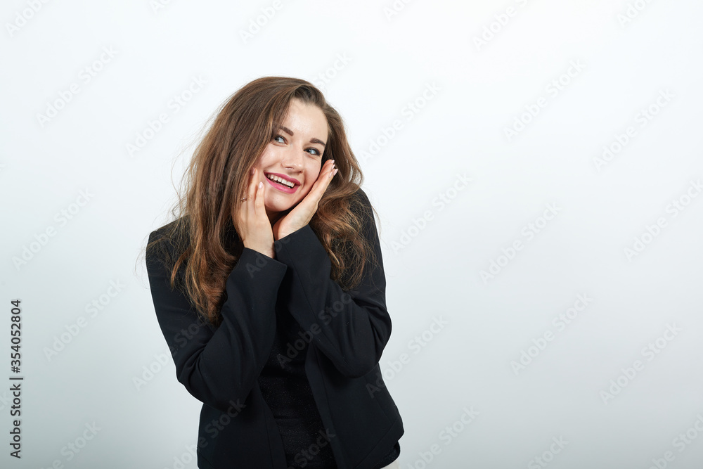 Young Attractive Woman Brunette In In A Black T-Shirt, Sweater On White Background, Cute Female Holds Hands Near Her Face. The Concept Tenderness And Kindness Of People Young Attractive Woman Brunette In In A Black T-Shirt, Sweater On White Background, Cute Female Holds Hands Near Her Face. The Concept Tenderness And Kindness Of People