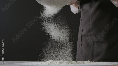 Falling slowly flour on a wooden dark table from sifter on a black background. Slow motion, Full HD video, 240fps, 1080p. Process preparing of homemade pastry.