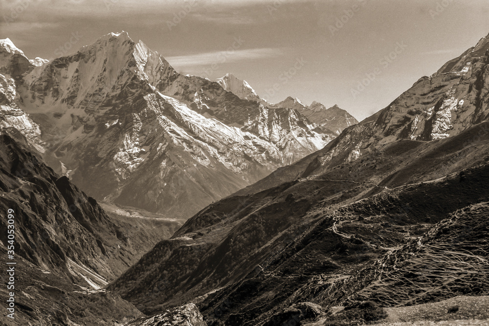 Colossal snowy mountains and deep valleys amid the Himalayas. The world largest and highest mountain range, in northern Nepal. Black and white photo.