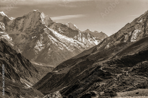 Colossal snowy mountains and deep valleys amid the Himalayas. The world largest and highest mountain range, in northern Nepal. Black and white photo.