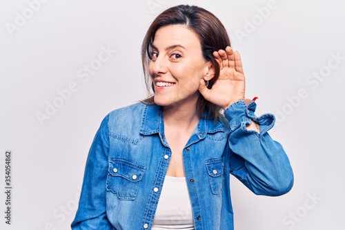 Young beautiful woman wearing casual clothes smiling with hand over ear listening and hearing to rumor or gossip. deafness concept.