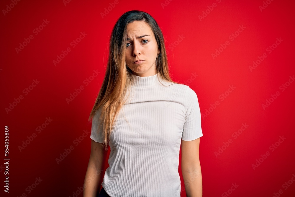 Beautiful blonde woman with blue eyes wearing casual white t-shirt over red background depressed and worry for distress, crying angry and afraid. Sad expression. Beautiful blonde woman with blue eyes wearing casual white t-shirt over red background depressed and worry for distress, crying angry and afraid. Sad expression.