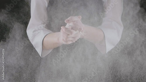 Chef is clapping his hands filled with flour on a black background. Slow motion, Full HD video, 240fps, 1080p. Process preparing of homemade pastry.