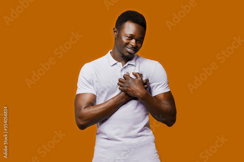 Relaxed black man closes eyes and hugs themselves. Calm and pacification of a african man. Public influence on skin color. Tolerance to african nationality