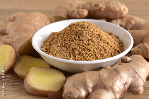 Fototapeta Naklejka Na Ścianę i Meble -  Ginger powder in a white bowl and fresh ginger root on a wooden background.