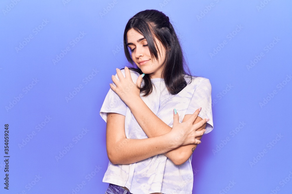 Young beautiful girl wearing casual t shirt hugging oneself happy and positive, smiling confident. self love and self care Young beautiful girl wearing casual t shirt hugging oneself happy and positive, smiling confident. self love and self care