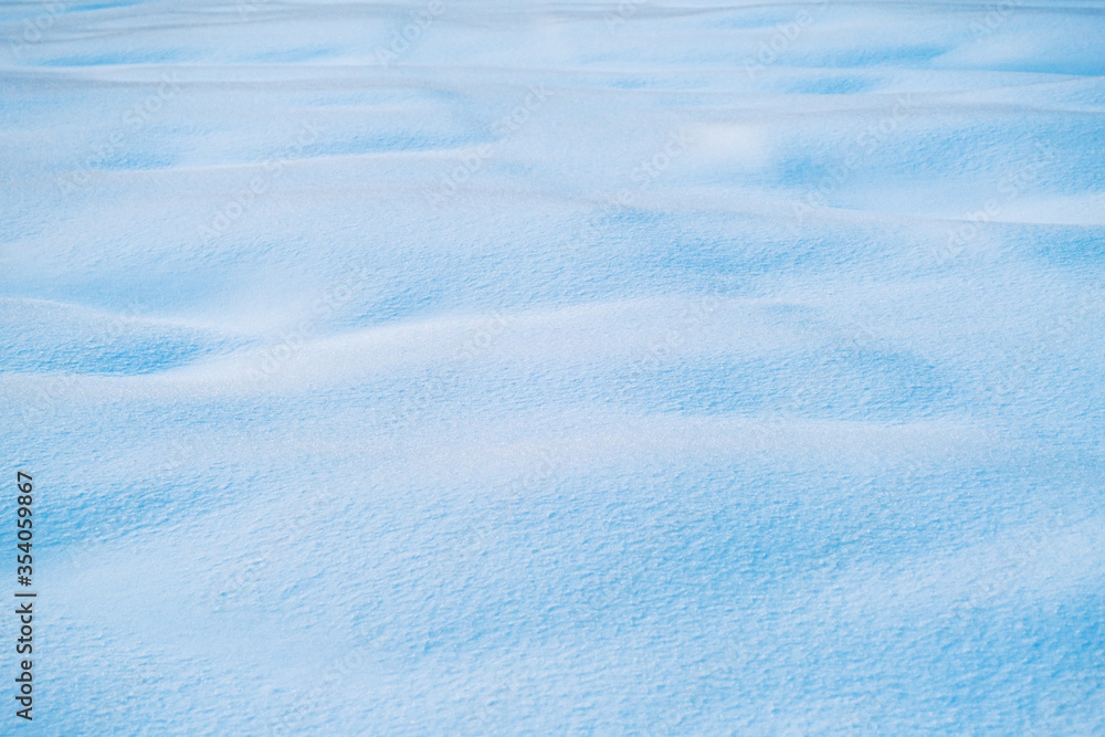 White and blue snowy texture of natural snow surface White and blue snowy texture of natural snow surface