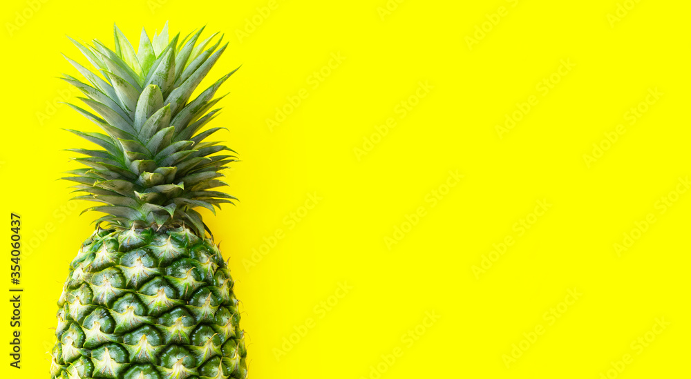 Single whole pineapple on yellow background.